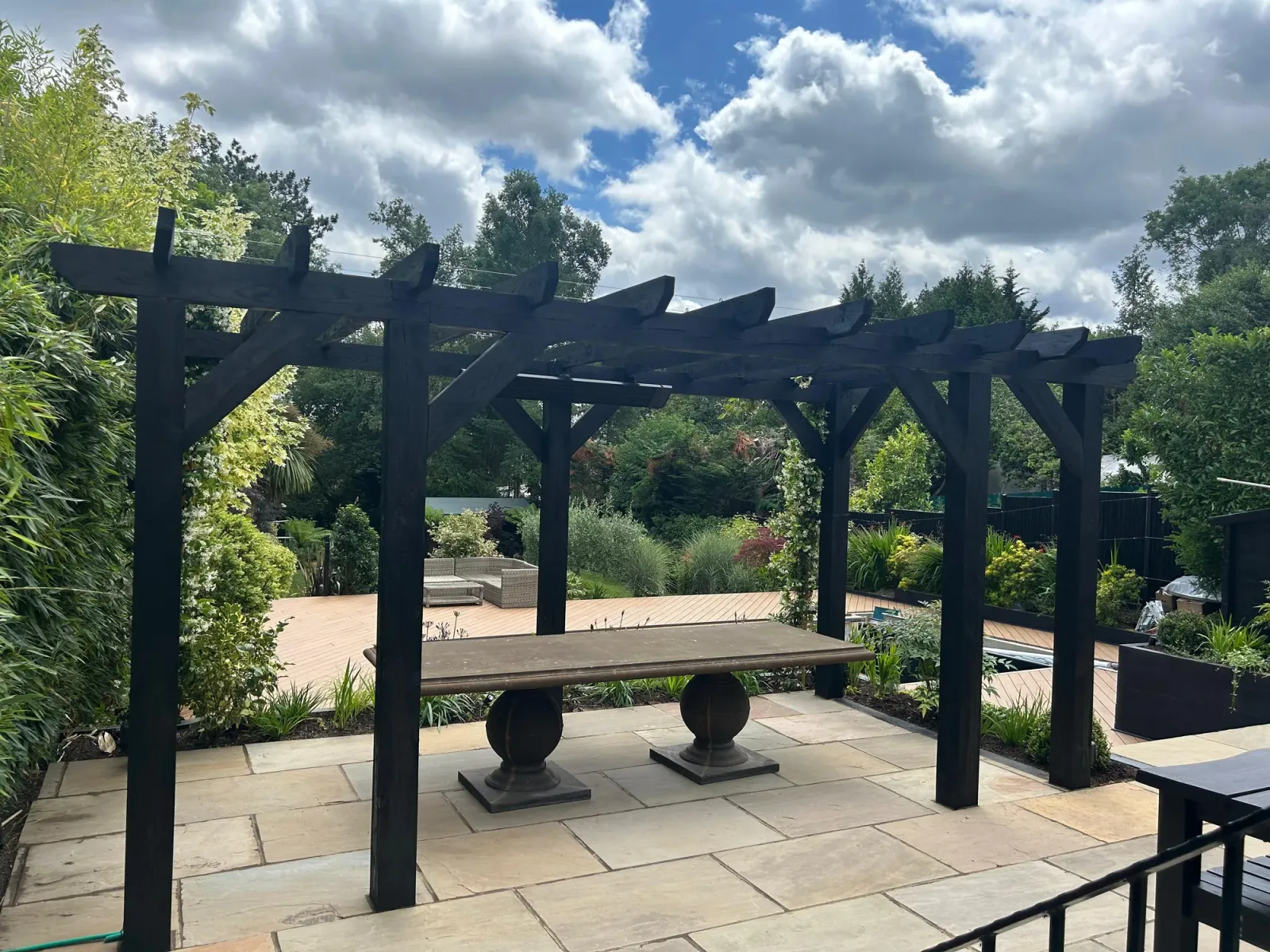 Custom dark timber pergola over a flagstone patio with garden table
