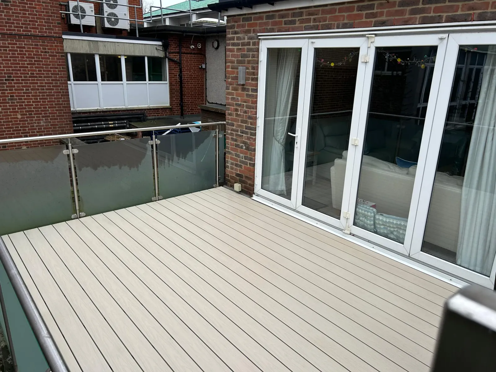 Whetstone N20: light composite decking on a glass-balustrade terrace, replacing rotted timber