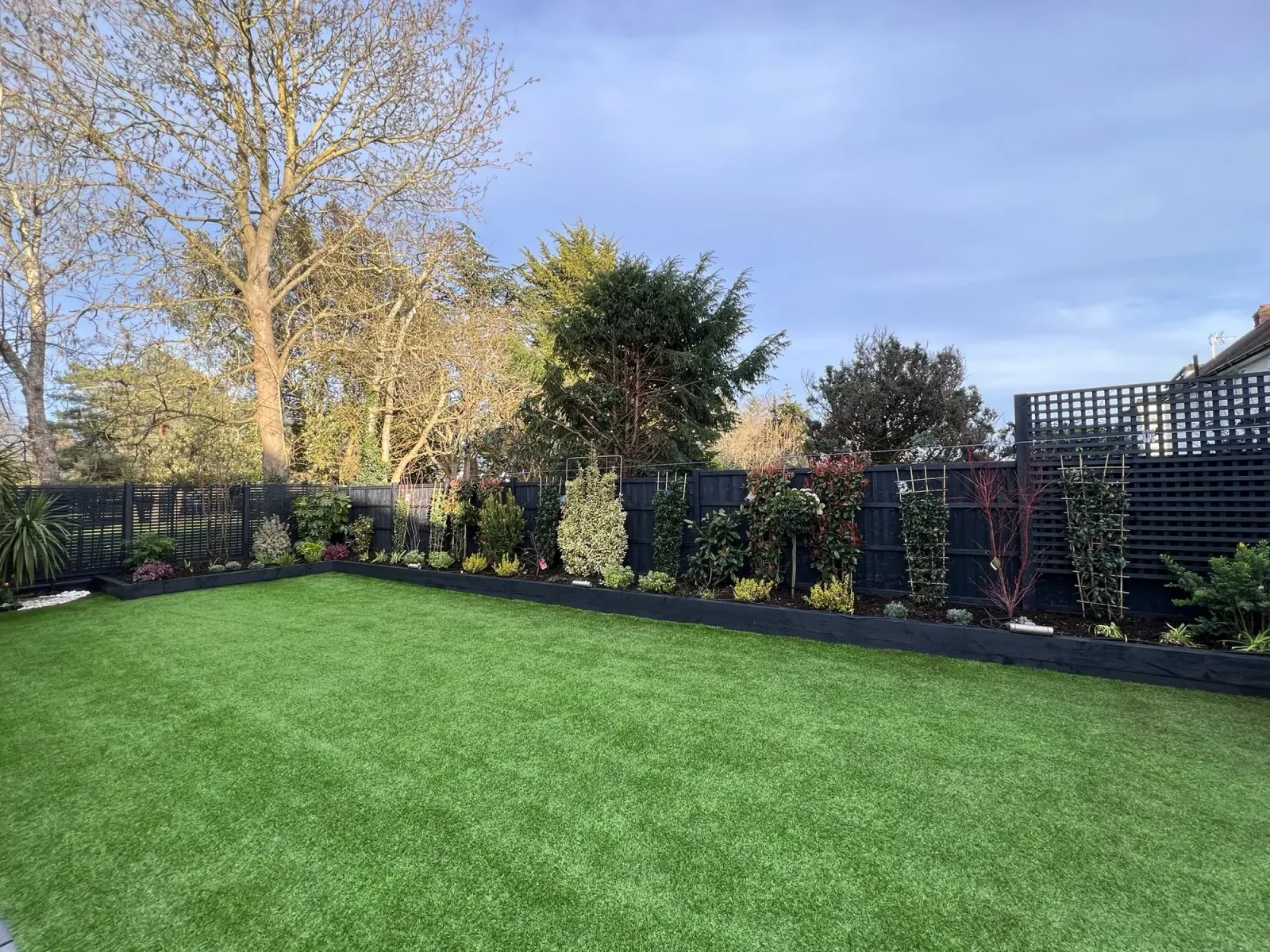 Finchley Central N3: clean lawn bordered by black-painted timber fence and Chelsea trellises