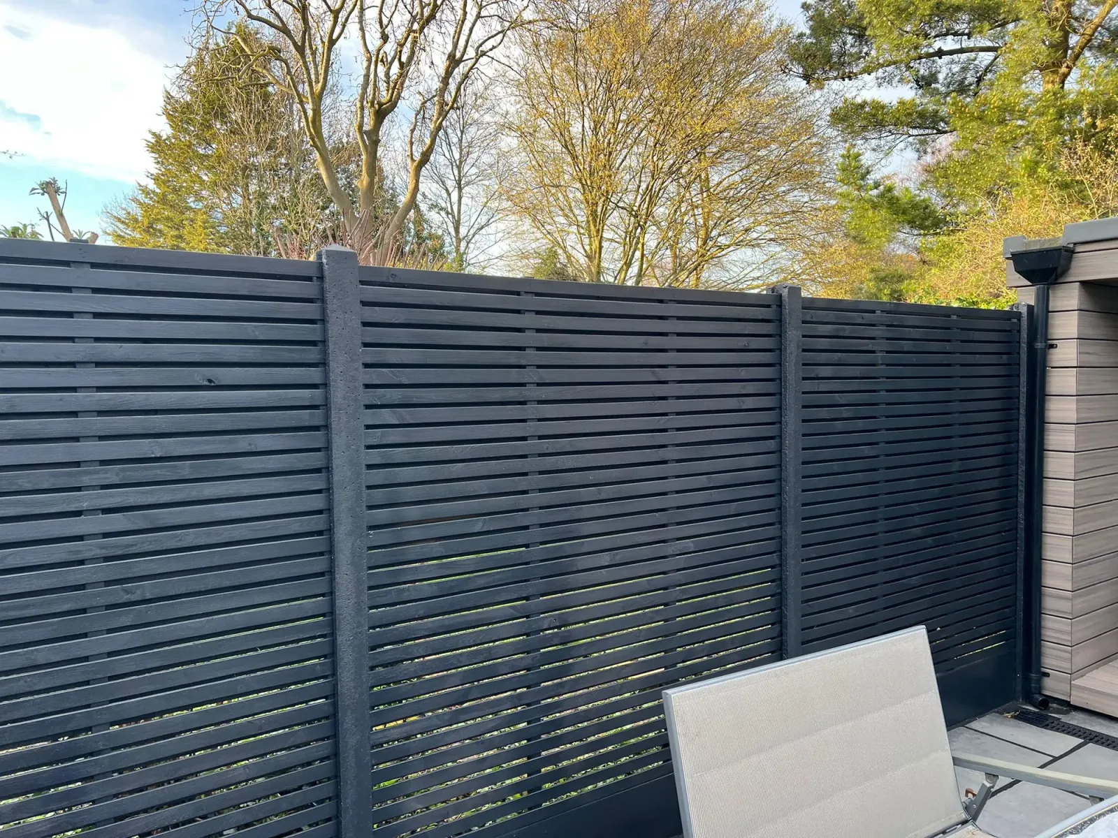 Detail of the new dark slatted fence panels with horizontal slats